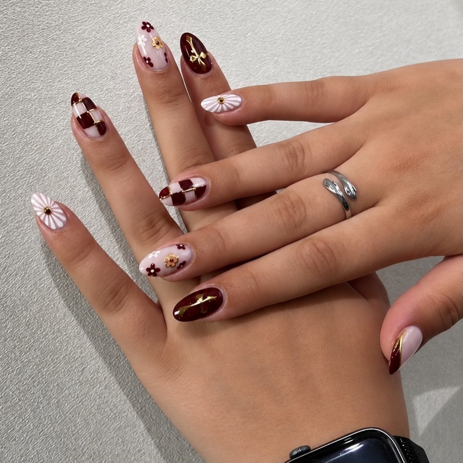 Bordeaux nagels met schaakbordpatroon, bloemen en gouden charms