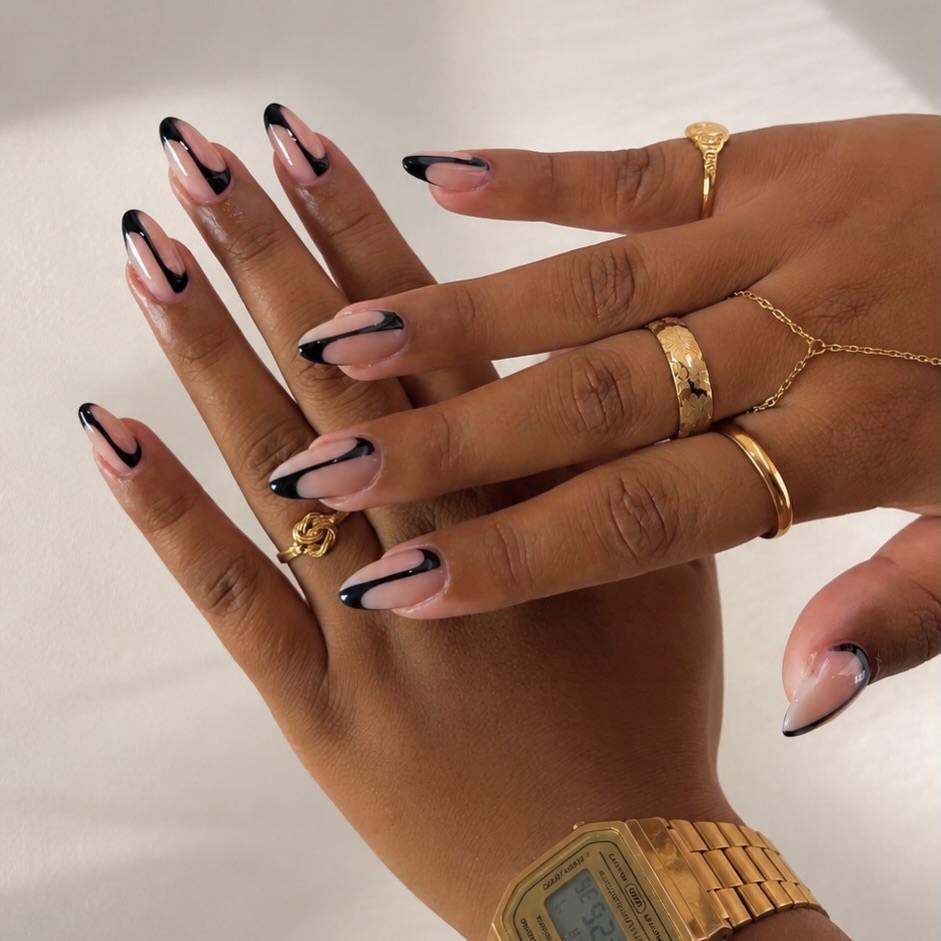 Almond nagels met zwarte wave French en gouden ringen